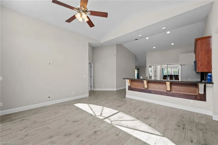 Unfurnished living room featuring light wood-style flooring, a ceiling fan, recessed lighting, and lofted ceiling