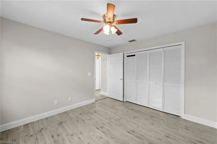 Unfurnished bedroom with light wood-style floors, ceiling fan, and a closet