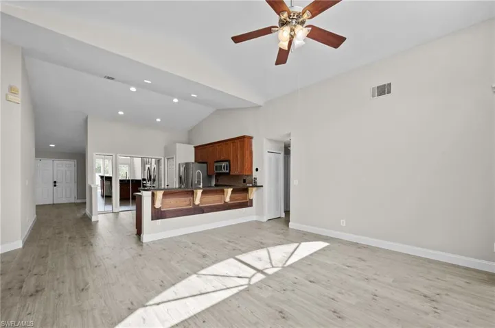 Unfurnished living room with light wood-style floors, a ceiling fan, lofted ceiling, and recessed lighting