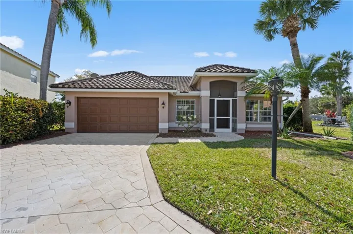 Mediterranean / spanish house featuring stucco siding, driveway, a front lawn, and a tile roof