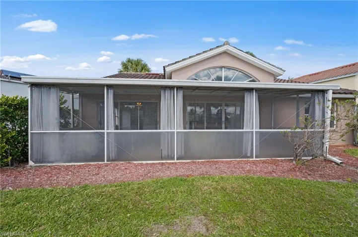 Rear view of house with a yard and a sunroom