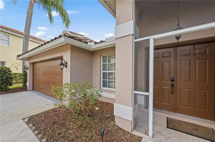 Entrance to property featuring stucco siding, driveway, an attached garage, and a tile roof