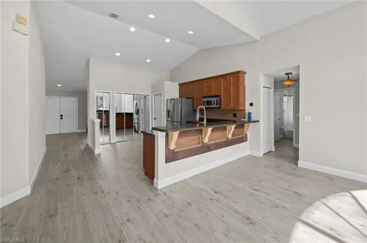 Kitchen featuring wood finish cabinetry, a peninsula, a kitchen bar, light wood-style floors, and stainless steel appliances