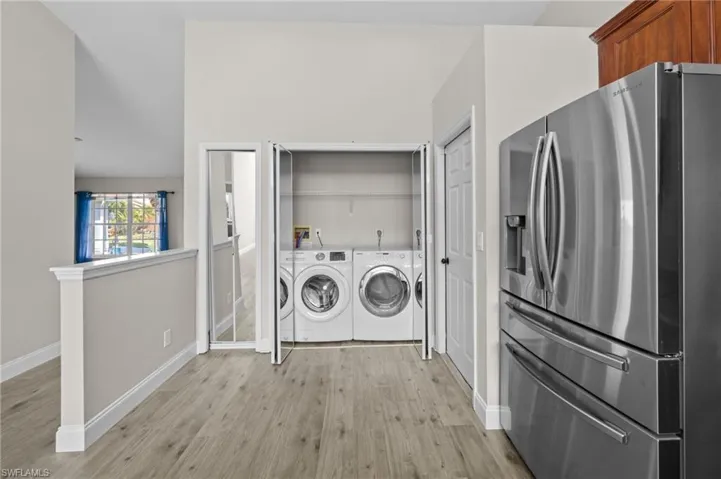 Laundry area with separate washer and dryer and light wood finished floors