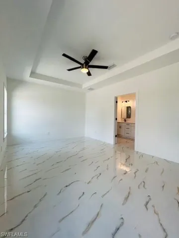 Empty room featuring a raised ceiling and ceiling fan