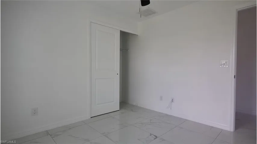 Unfurnished room with a ceiling fan, marble finish floor, baseboards, and visible vents