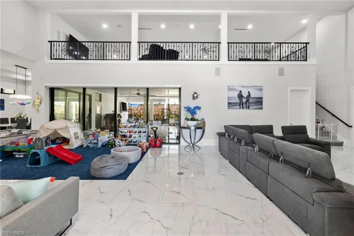 Living room featuring a high ceiling, recessed lighting, and light marble finish floors