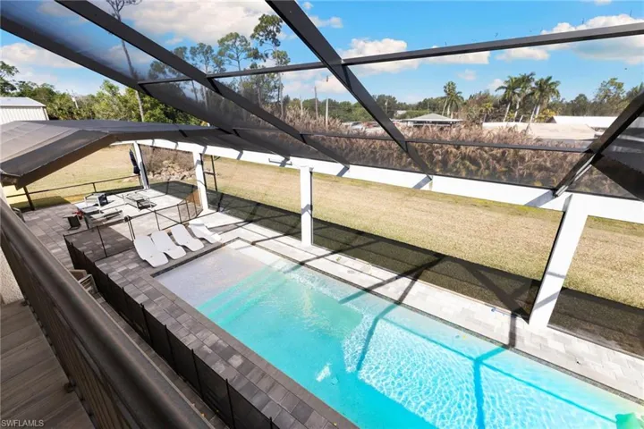 Outdoor pool featuring a lanai, a yard, and a sunroom