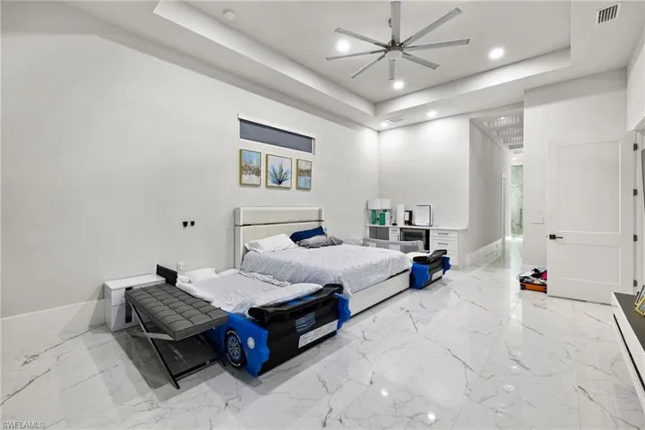 Bedroom with a raised ceiling, ceiling fan, and recessed lighting