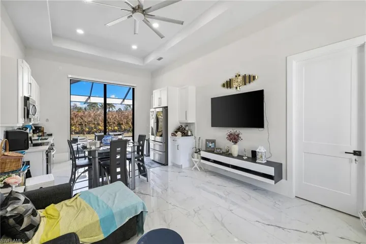 Living room with ceiling fan, light marble finish flooring, recessed lighting, and a raised ceiling