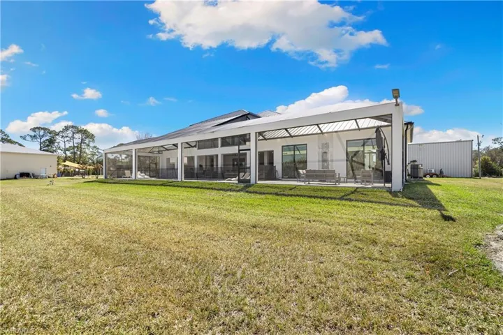 Rear view of house with a lawn, a lanai, a sunroom, and a patio area