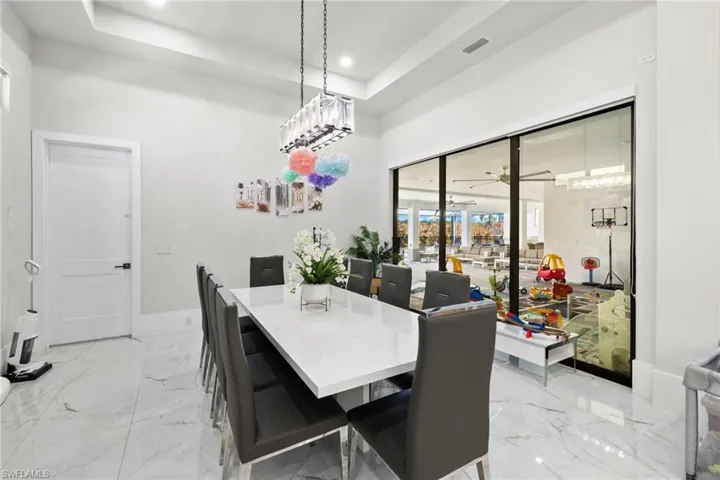Dining room featuring recessed lighting, ceiling fan, a raised ceiling, and light marble finish floors