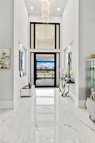 Foyer with a high ceiling, light marble finish floors, and suspended lighting