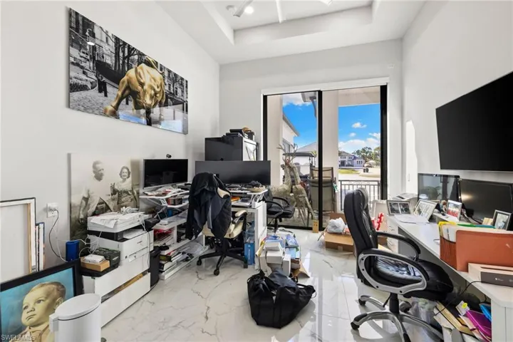 Office with a tray ceiling and light marble finish floors