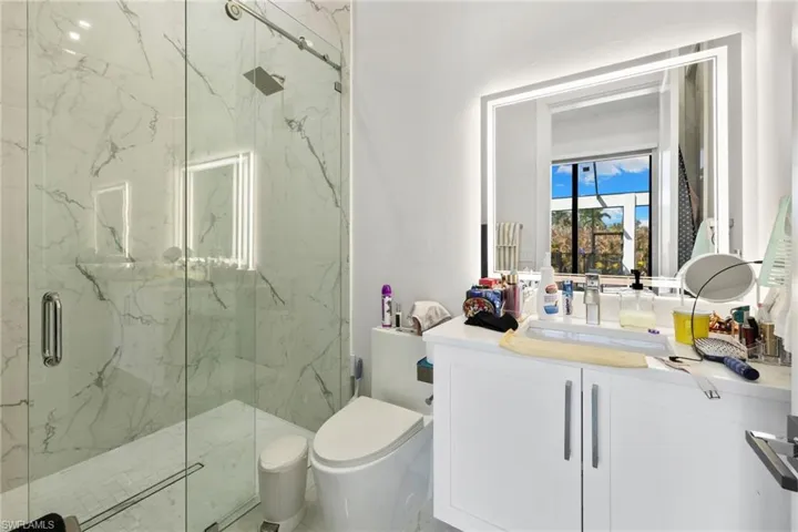 Bathroom with vanity and a marble finish shower