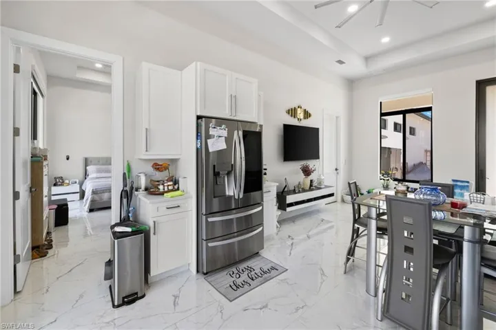 Kitchen featuring a raised ceiling, stainless steel fridge, white cabinets, recessed lighting, and ceiling fan