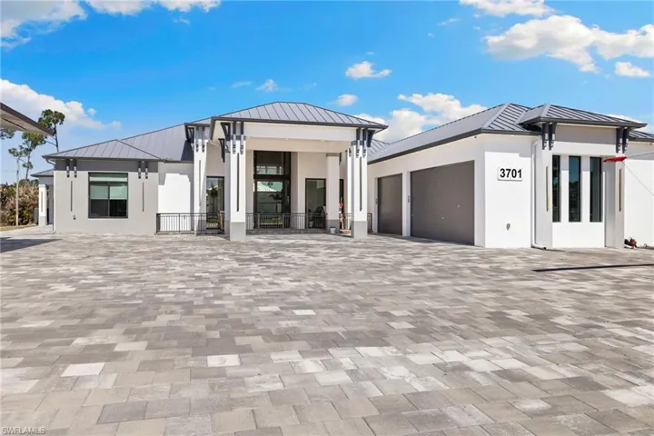 View of front of home with a standing seam roof, stucco siding, and driveway