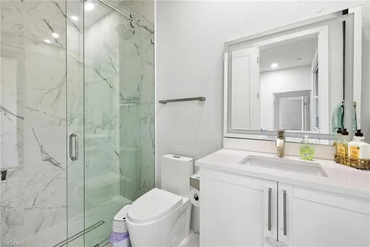 Bathroom featuring vanity and a marble finish shower