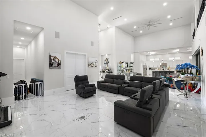Living room featuring recessed lighting, a high ceiling, a ceiling fan, and light marble finish flooring