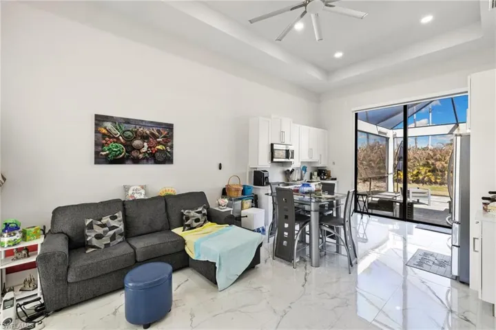 Living room with a sunroom, a raised ceiling, ceiling fan, recessed lighting, and light marble finish floors