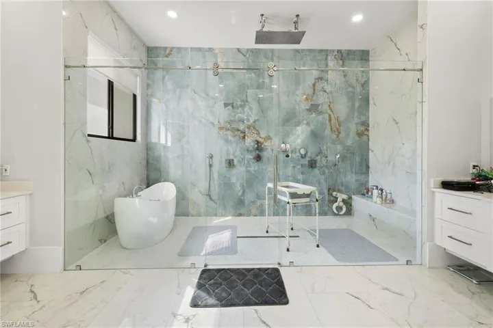 Bathroom with vanity, a marble finish shower, and stone wall