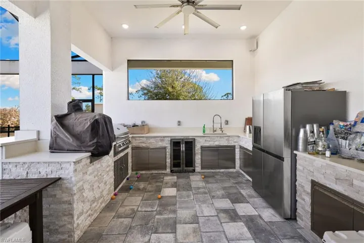 View of patio featuring exterior kitchen, a ceiling fan, and wine cooler