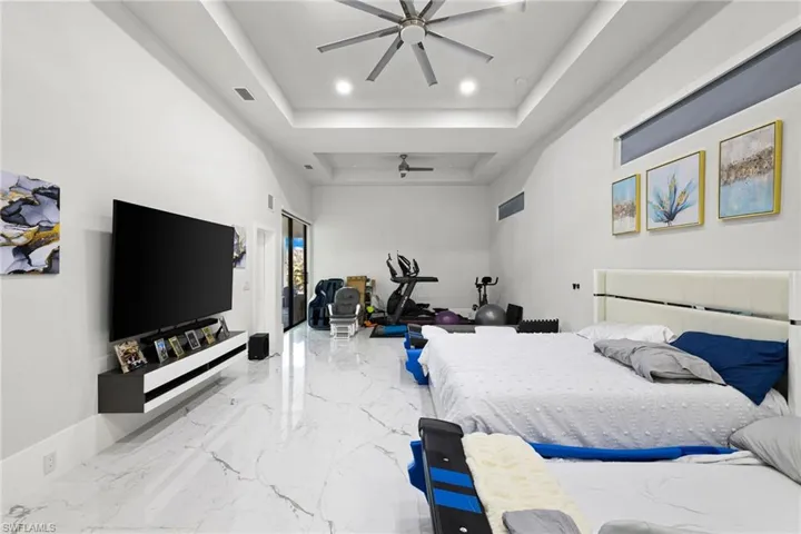 Bedroom with recessed lighting, a high tray ceiling, and light marble finish flooring
