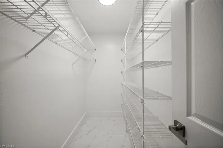 Walk in closet featuring light marble finish flooring