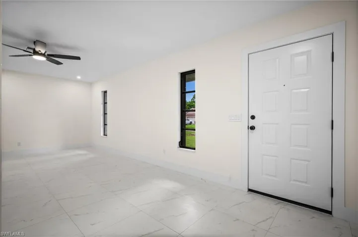 Spare room featuring light marble finish floors and baseboards