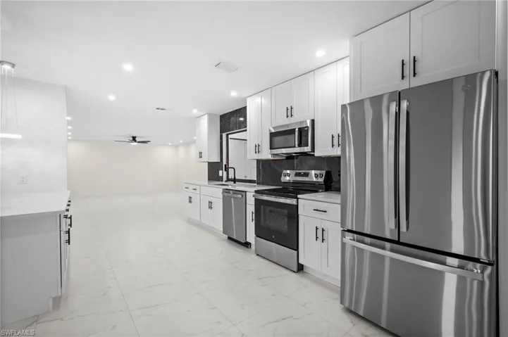 Kitchen featuring stainless steel appliances, white cabinetry, recessed lighting, and a ceiling fan