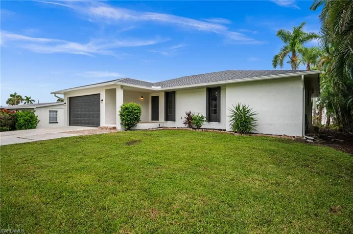 Ranch-style house featuring stucco siding, driveway, a front lawn, and an attached garage