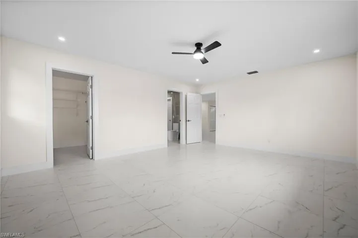 Unfurnished bedroom with light marble finish flooring, a spacious closet, recessed lighting, ceiling fan, and connected bathroom