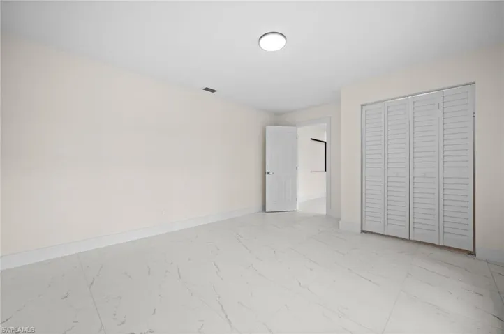 Unfurnished bedroom with light marble finish floors and a closet