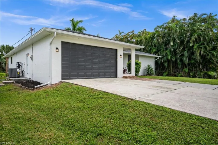View of front facade featuring driveway, stucco siding, a front lawn, and an attached garage