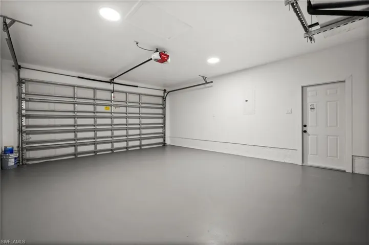 Garage with recessed lighting, electric panel, and a garage door opener