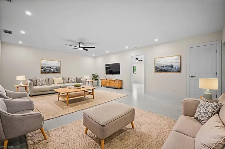Living area featuring ceiling fan, recessed lighting, and light marble finish flooring
