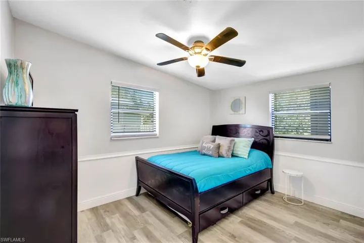 Bedroom featuring wood finished floors, multiple windows, and a ceiling fan