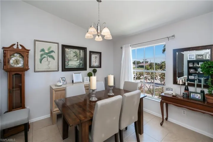 Dining space with a chandelier, light tile patterned floors, and baseboards