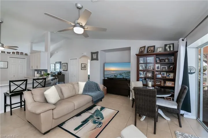 Living room featuring ceiling fan, lofted ceiling, light tile patterned floors, and arched walkways