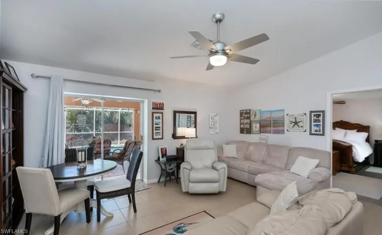 Living area with ceiling fan, lofted ceiling, light tile patterned flooring, and baseboards