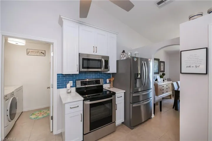 Kitchen featuring appliances with stainless steel finishes, washer and clothes dryer, light countertops, and arched walkways