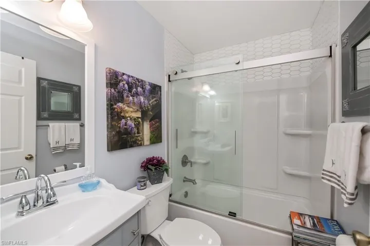 Bathroom with enclosed tub / shower combo, toilet, and vanity