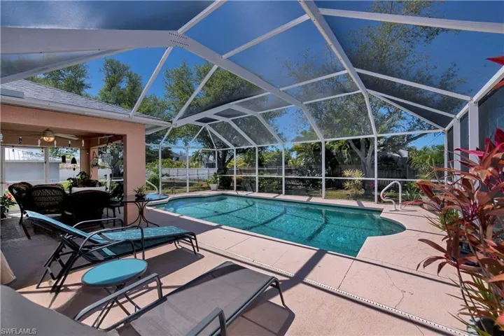 Swimming pool featuring a patio area, a fenced backyard, and glass enclosure