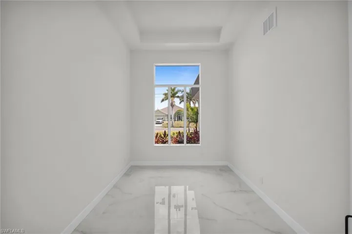 Unfurnished room with marble finish floor, visible vents, a raised ceiling, and baseboards