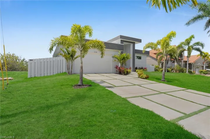 View of front of house with driveway, stucco siding, fence, a front lawn, and a garage