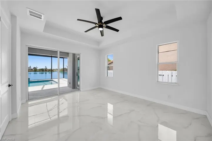 Empty room with visible vents, a tray ceiling, and baseboards