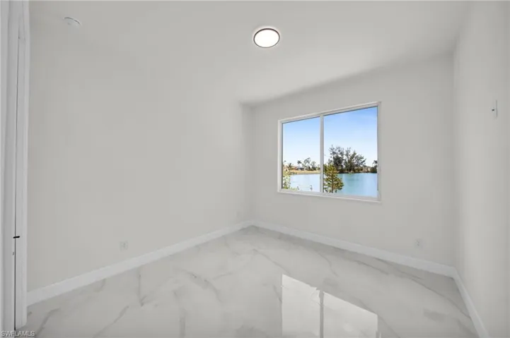 Empty room featuring baseboards, a water view, and marble finish floor