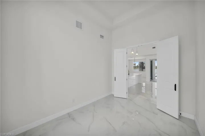 Empty room featuring visible vents, a high ceiling, marble finish floor, and baseboards