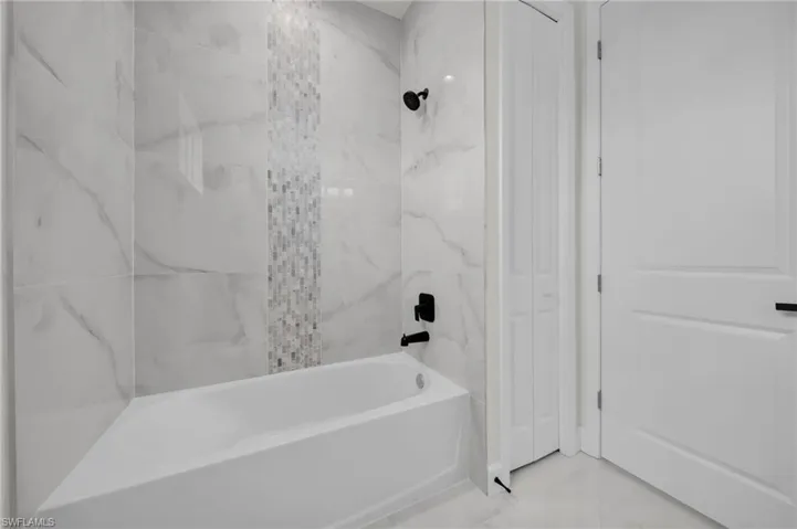 Bathroom with marble finish floor and shower / bath combination