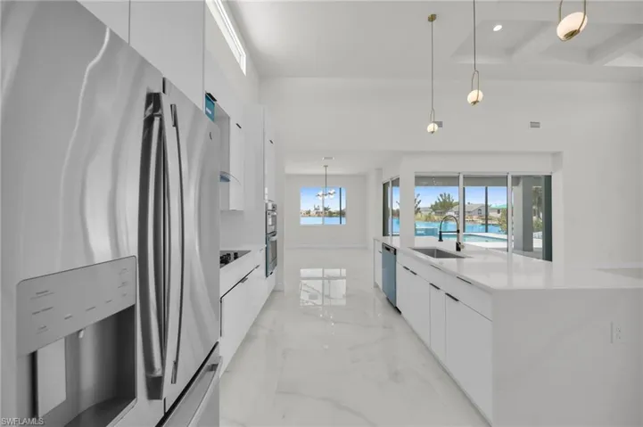 Kitchen with appliances with stainless steel finishes, marble finish floor, white cabinets, a sink, and modern cabinets